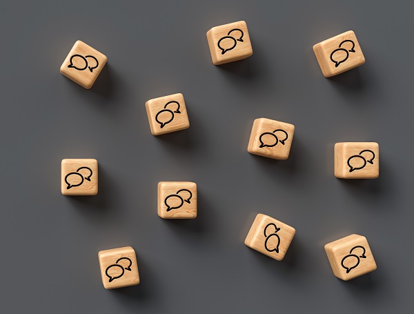 many cubes with speech bubble icons and smartphone on wooden bac